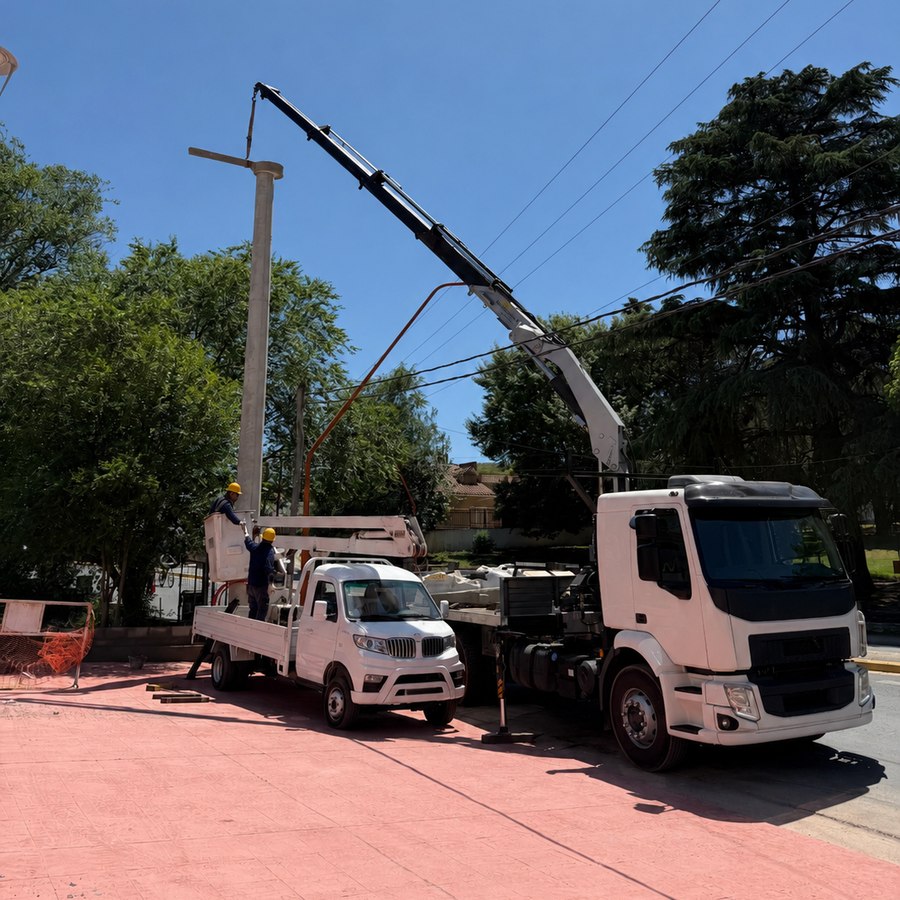 Camiones y grúa de Inelmap montando un poste de hormigón en la obra del Hotel AGEC